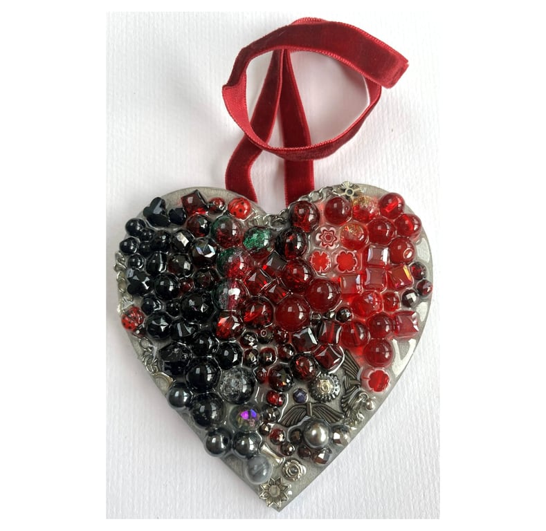 A wooden heart shaped pendant with ruby and black coloured spheres.