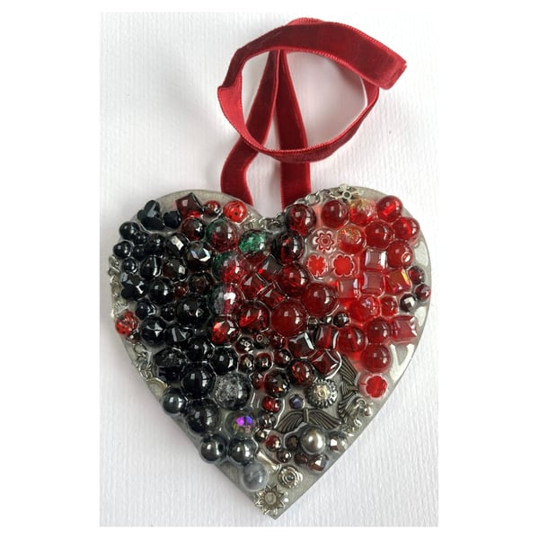 A wooden heart shaped pendant with ruby and black coloured spheres.