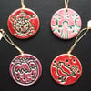 Set of four red, pink and plum ceramic Christmas decorations