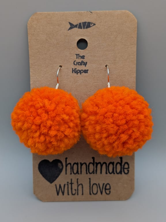 Handmade orange dangle pom pom earrings.