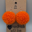 Handmade orange dangle pom pom earrings.