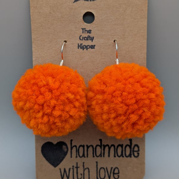 Handmade orange dangle pom pom earrings.