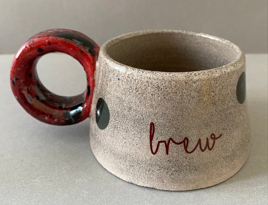 Brew. Ceramic cup. Polka dots and red handle.