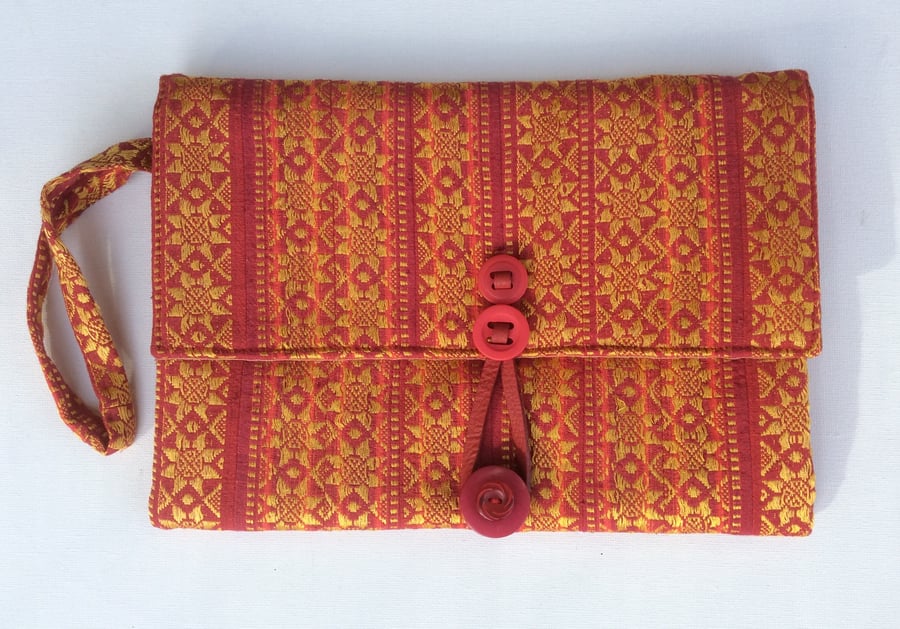 Red and gold clutch bag with wrist strap.