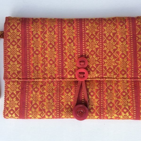 Red and gold clutch bag with wrist strap.