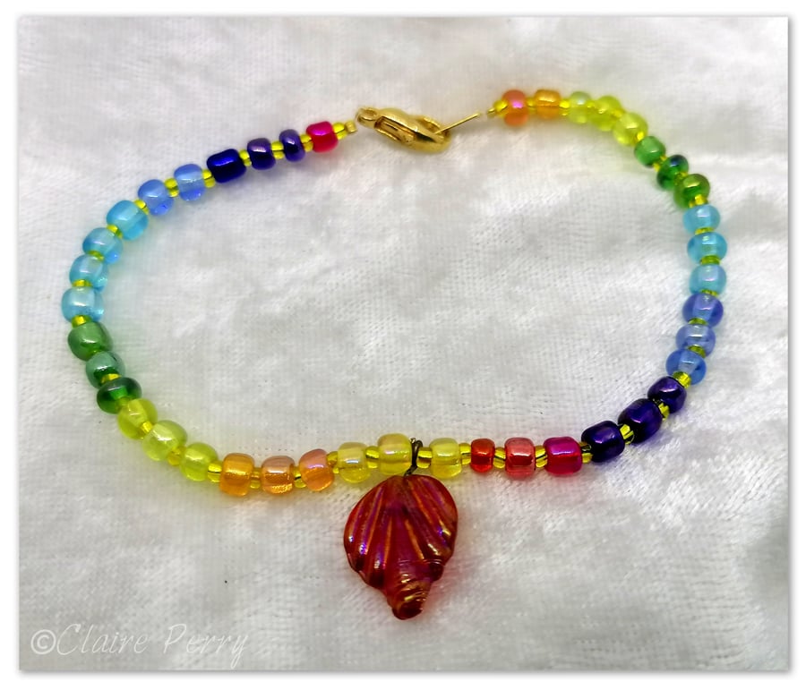 Seed bead bracelet with rainbow coloured glass beads with a red glass charm.