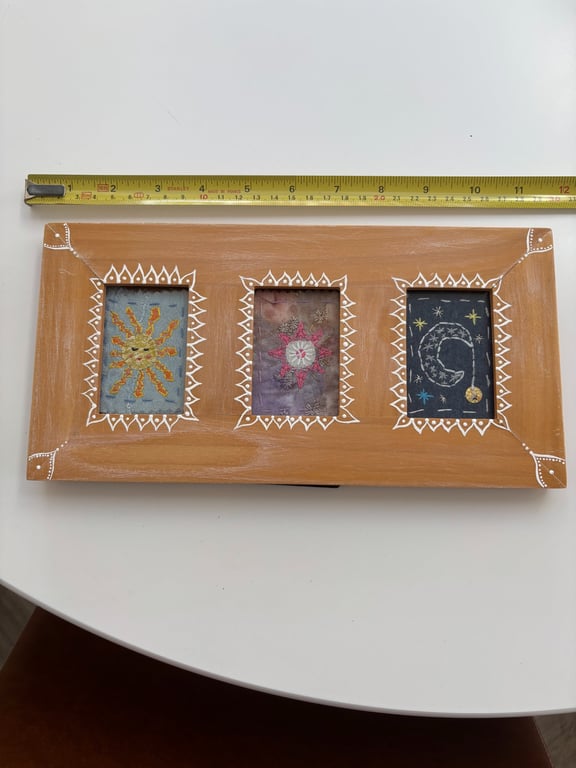 Sun star and moon hand stitched textile picture in a painted wooden frame.