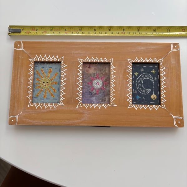 Sun star and moon hand stitched textile picture in a painted wooden frame.