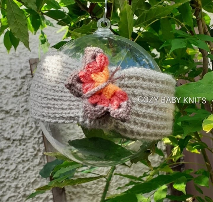  ARAN BABY EARWARMER WITH A BUTTERFLY APPLIQUED ON IT