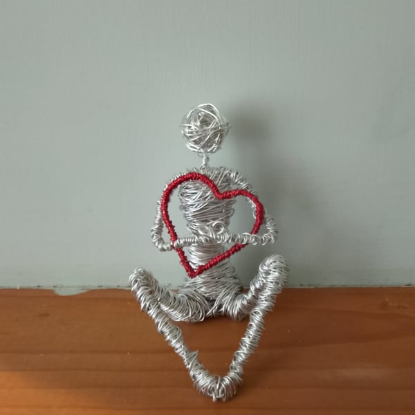 Figure Holding onto love wire art sculpture 