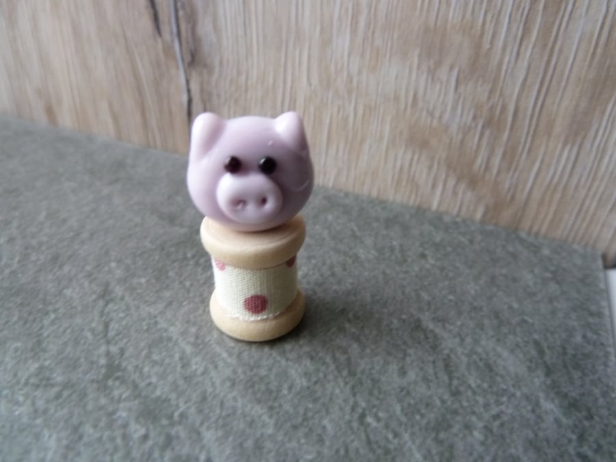 glass pig on a wooden bobbin