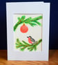 Festive robin on evergreen branches, with red bauble