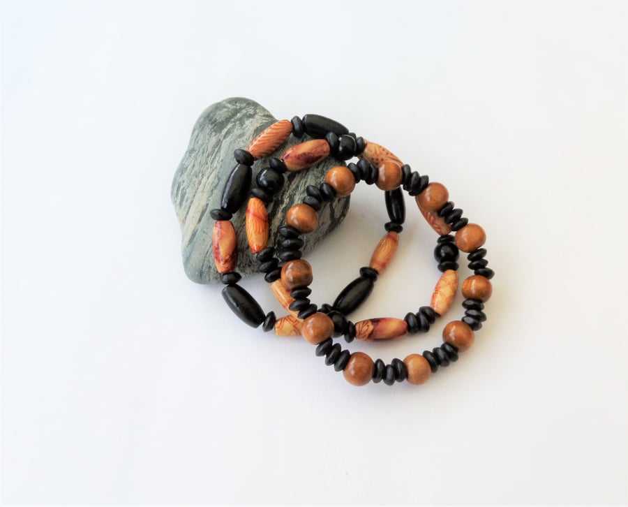 Three brown, black and patterned dyed wooden elasticated bracelets, no metal
