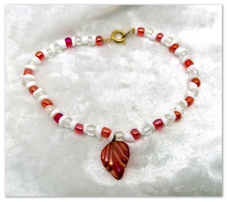 Seed bead bracelet with red and white glass beads with a red glass charm.