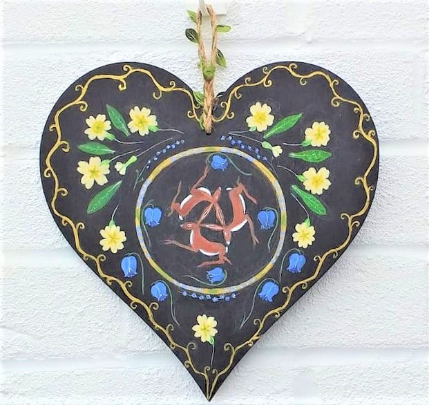 Hares and primroses on a wooden heart