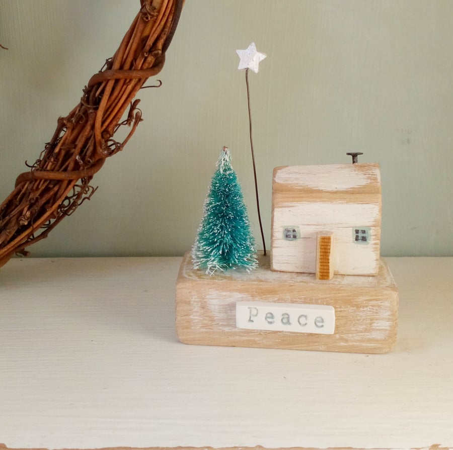 Little wooden house with Christmas tree and star 'peace'