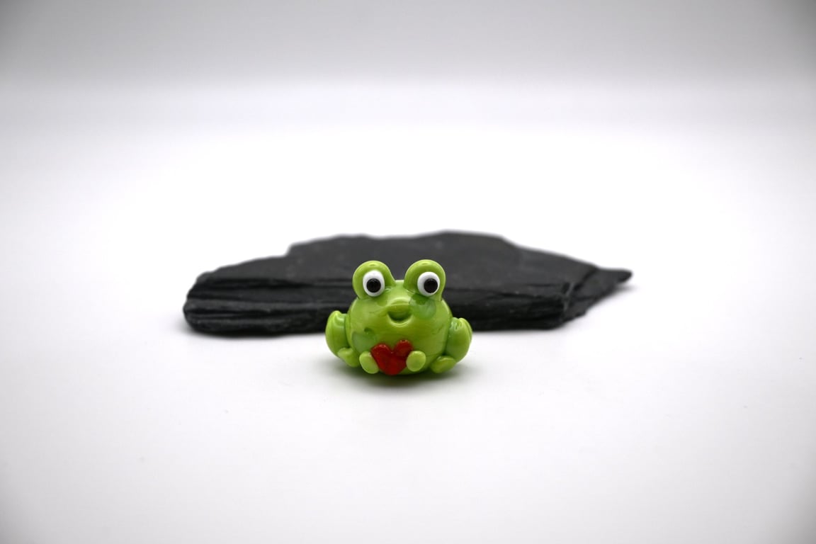 small glass frog holding a heart figure