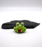 small glass frog holding a heart figure