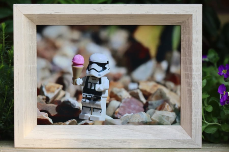 Framed photo of Lego figures, stormtrooper having a ice cream on the rocks.