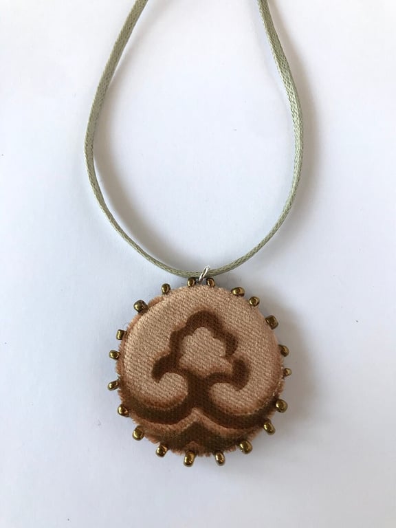 Gold pendant necklace with embossed velvet design and beaded edging.