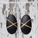 Black pebble earrings, inspired by nature with gold lines and silver earwires