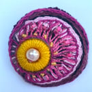 Hand embroidered circular brooch in shades of pink with added beads