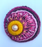 Hand embroidered circular brooch in shades of pink with added beads