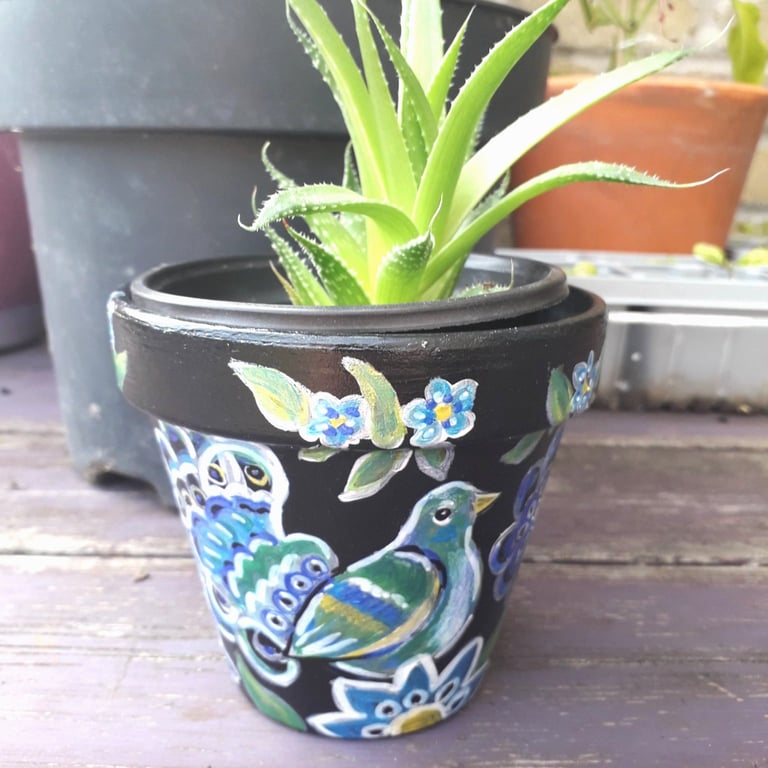 Terracotta plant pot handpainted with an ornamental bird and flowers.  