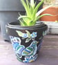 Terracotta plant pot handpainted with an ornamental bird and flowers.  