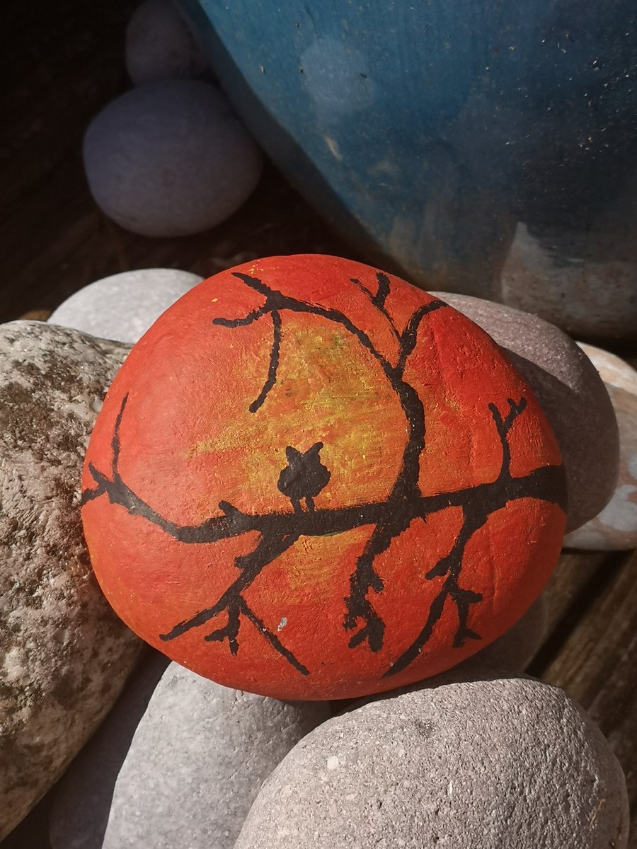 Painted orange and red pebble rock with owl in tree. 