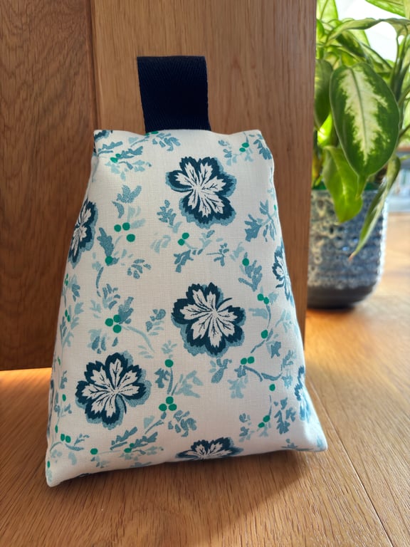 Cotton fabric doorstop in floral blue and green print, filled with pebbles.