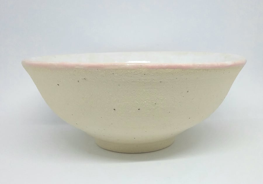 Handthrown pottery bowl in speckled clay with white shiny glaze and pink rim