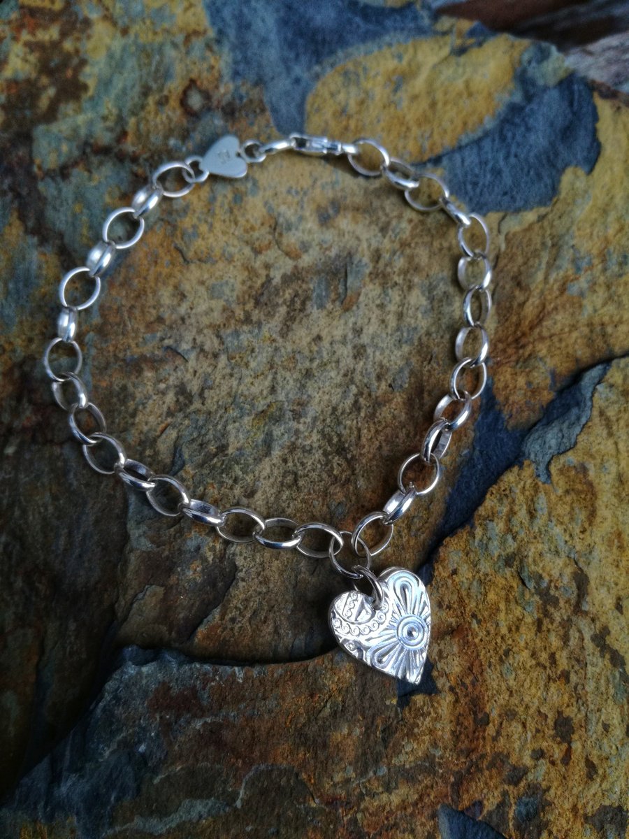 Silver bracelet with a heart charm.