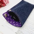 Denim glasses case with purple lining and a chrome popper.  