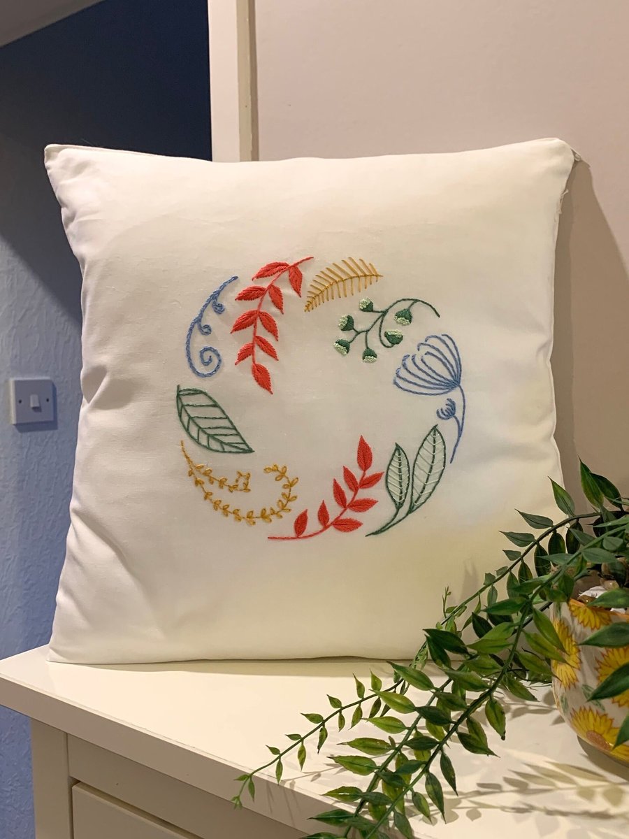 Cushion cover embroidered with a beautiful circle of leaves and flowers. 