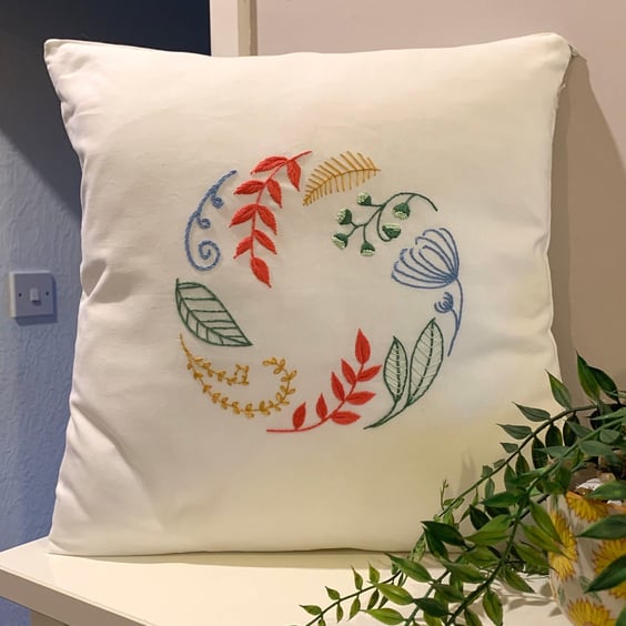 Cushion cover embroidered with a beautiful circle of leaves and flowers. 