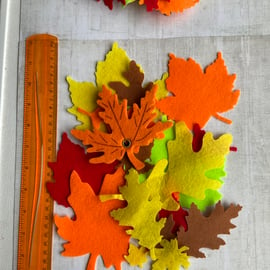 Large quantity of mixed felt leaves for crafting or appliqué in autumnal shades.