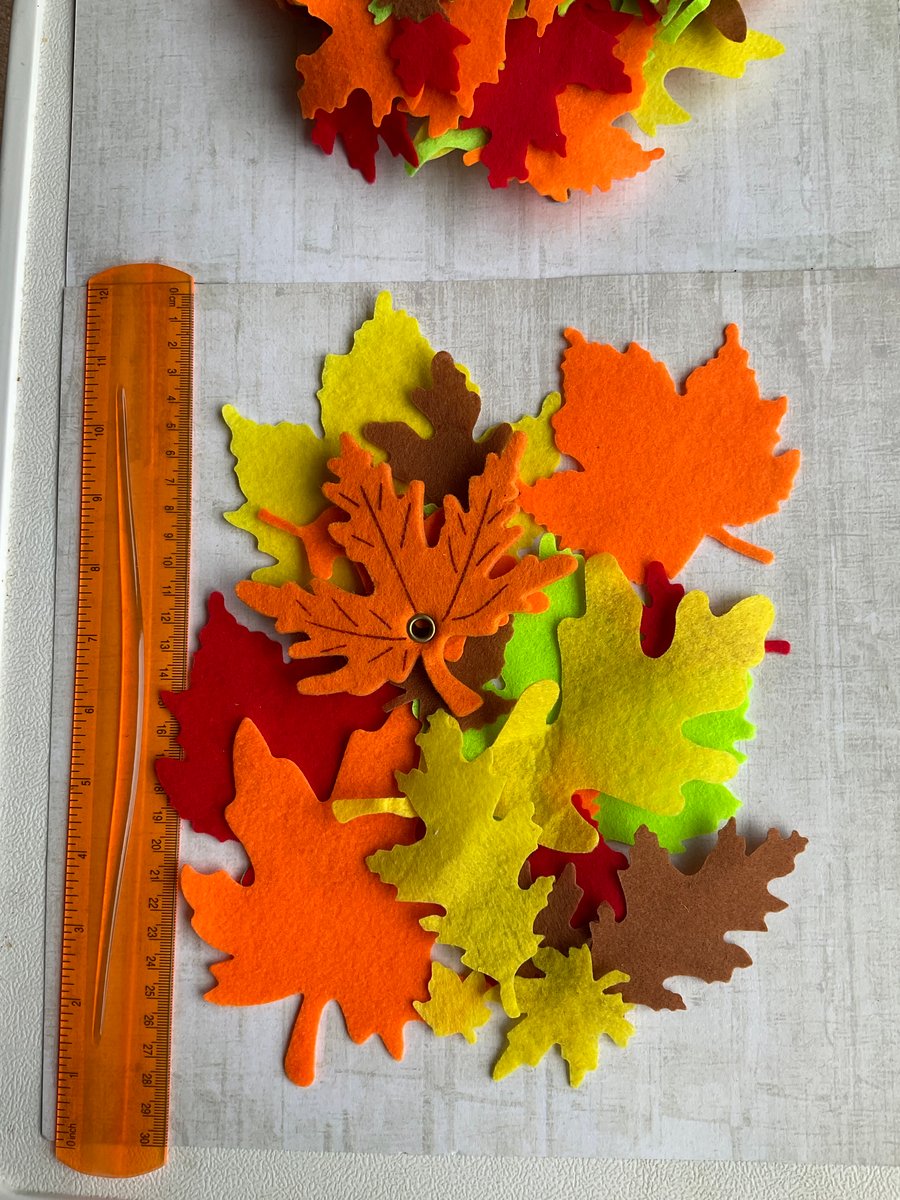 Large quantity of mixed felt leaves for crafting or appliqué in autumnal shades.