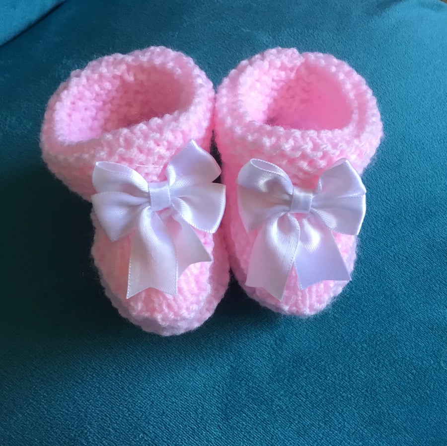 Hand knitted pale pink pink baby booties with a white satin bow fit 3 - 9 months
