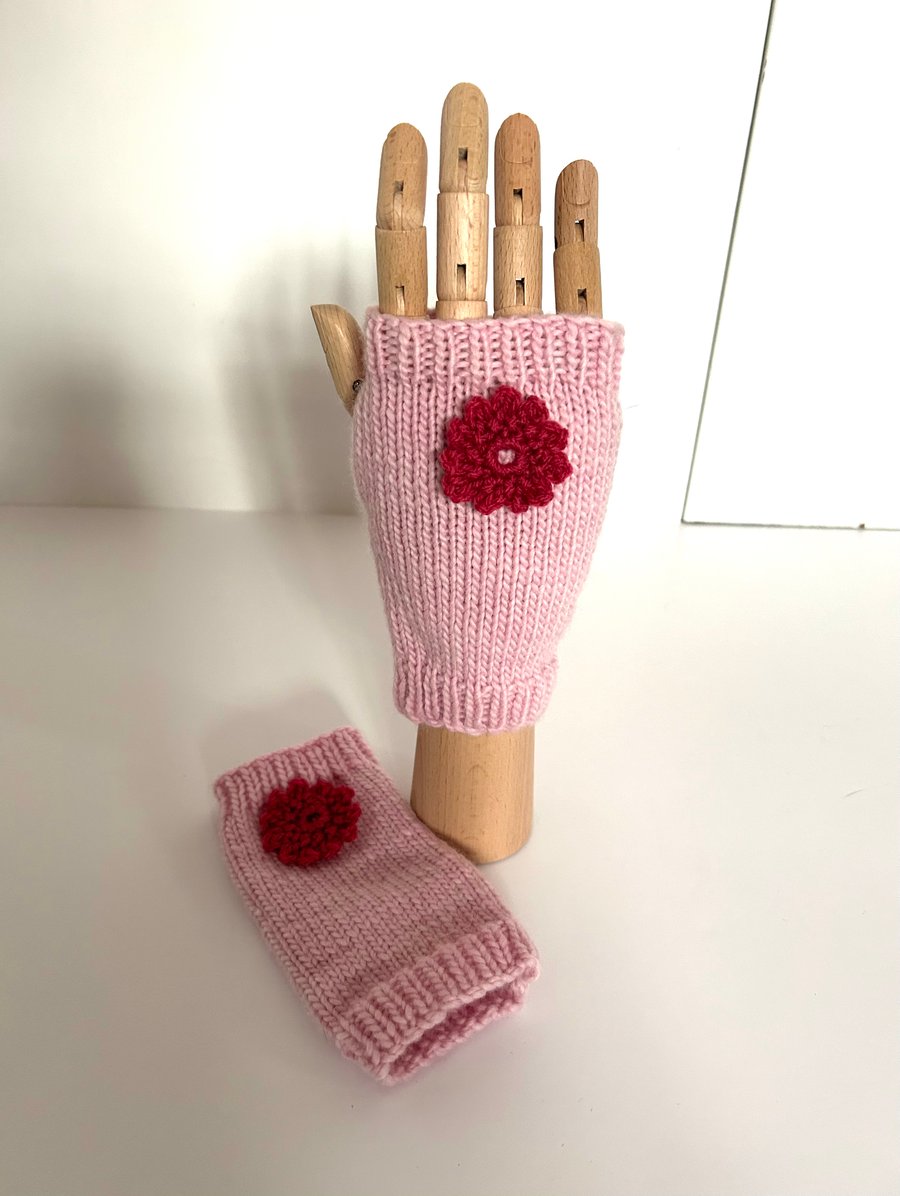 Hand knitted pink wrist warmers decorated with a crocheted flower