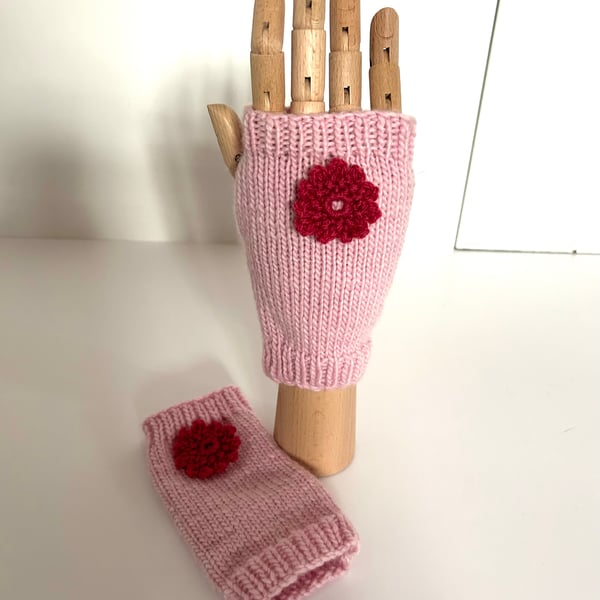 Hand knitted pink wrist warmers decorated with a crocheted flower