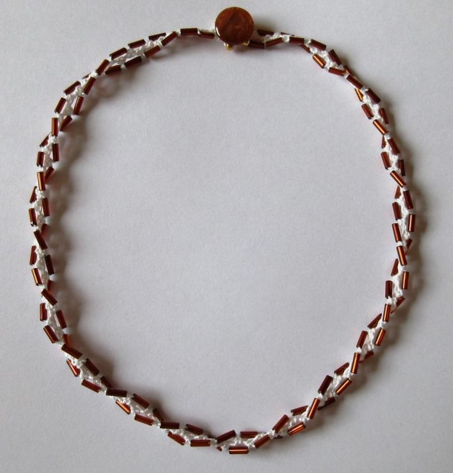 A crocheted necklace in white cotton with bronze bugle beads