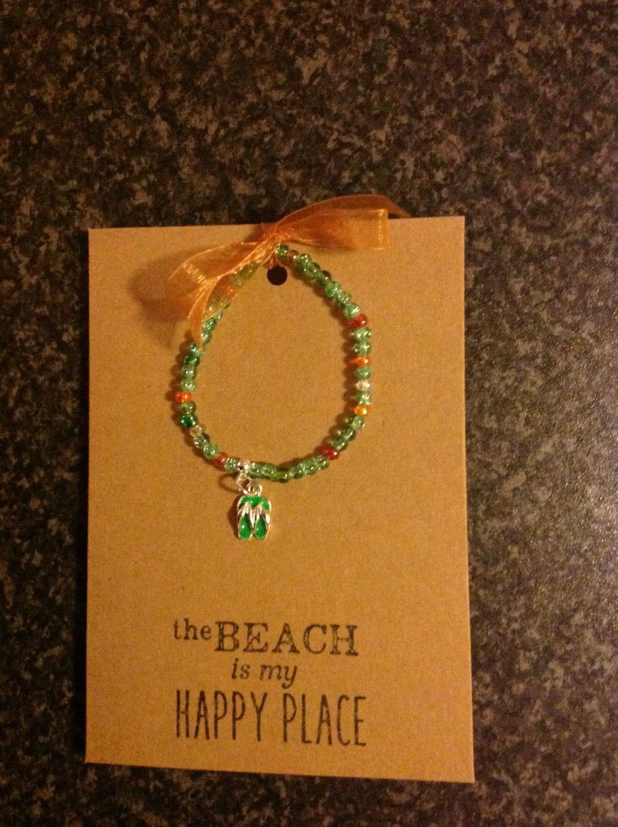 Stretch bracelet, hand strung, with charm attached, on an A6 card.
