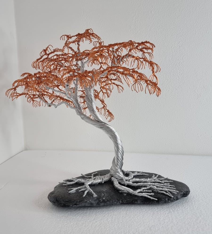 Silver and copper wire tree on grey slate.