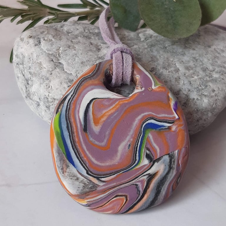 Handmade polymer clay oval pendant in a mauve, orange, black and green 