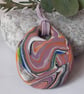 Handmade polymer clay oval pendant in a mauve, orange, black and green 
