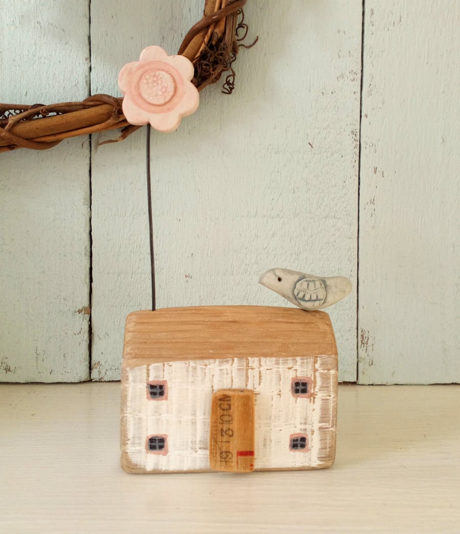 Little wooden house with clay flower and bird