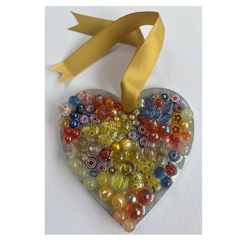 A wooden heart shaped pendant with blue, red, and yellow coloured spheres.