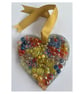 A wooden heart shaped pendant with blue, red, and yellow coloured spheres.