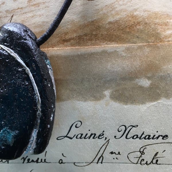 Concrete mullusc necklace with silver reflection.